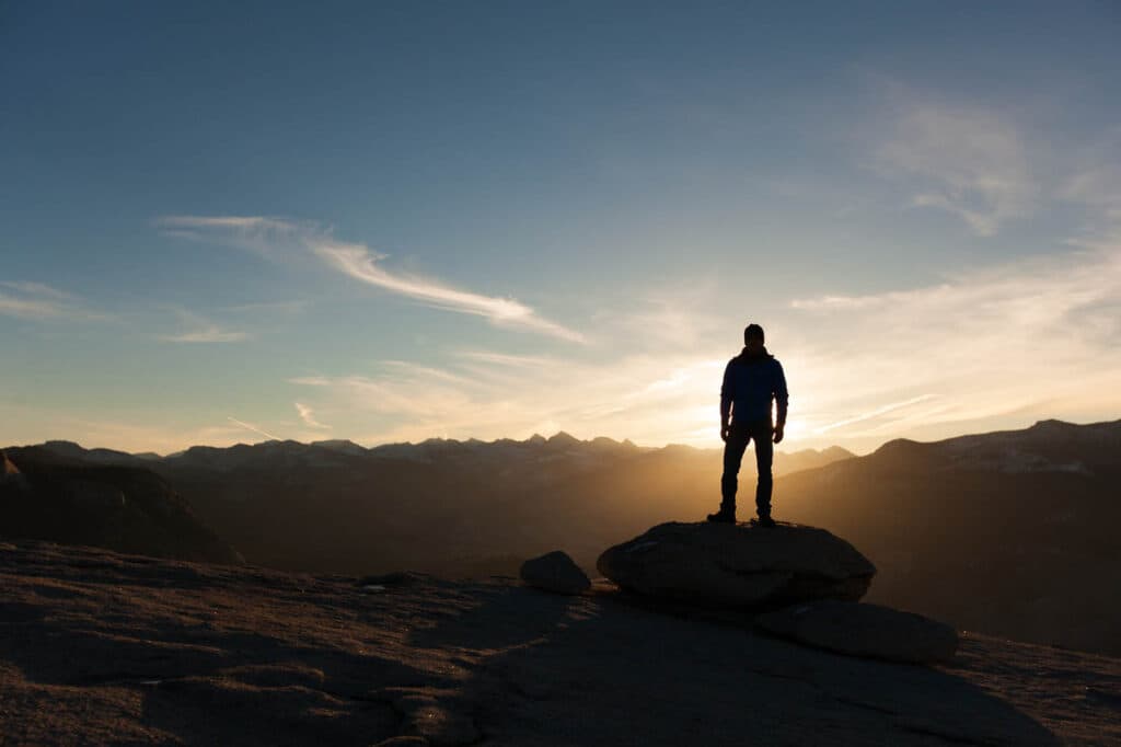 Person standing on a rock at sunrise